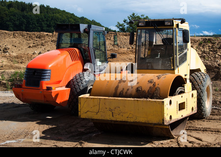 Gelb und orange Straßenwalzen geparkt auf einer Autobahn-Baustelle Stockfoto