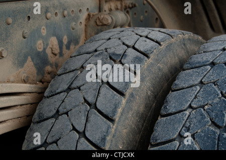 Nahaufnahme von großen Reifen und Fahrwerk von einem schmutzigen Muldenkipper Stockfoto