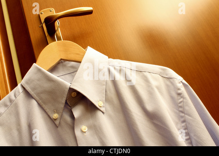 Shirt mit Kleiderbügel hängen von einem hölzernen Handgriff. Stockfoto