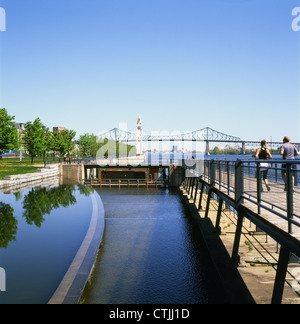 Läuferinnen joggen im Frühjahr am Lachine-Kanal und am Sankt-Lorenz-Strom und Blick auf die Jacques Cartier-Brücke Montreal Quebec Canada KATHY DEWITT Stockfoto