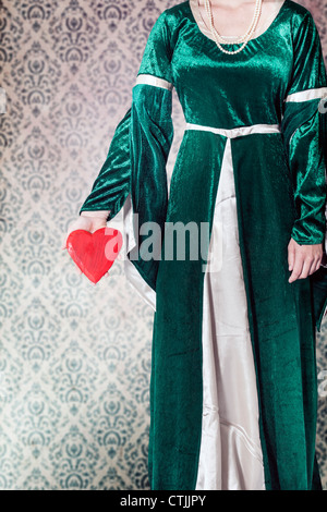 eine Frau in einem viktorianischen Kleid ein Herz in ihren Händen hält Stockfoto