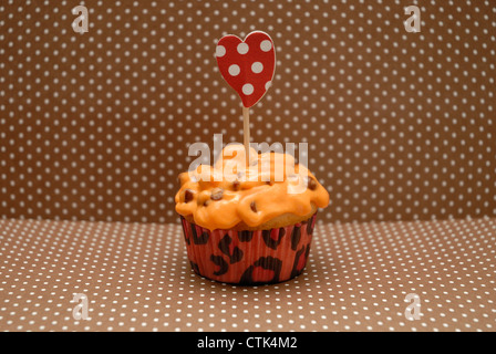 Eine hausgemachte Mini Cupcake mit orange farbigen Schokoladenkekse Zuckerguss. Stockfoto