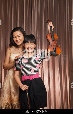 Porträt von fröhlichen Mutter mit ihrer süßen Tochter halten, Gitarre und Violine Stockfoto