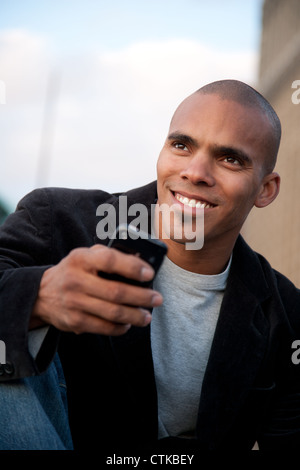 Glücklicher Mann mit Handy und wegschauen mit Neugier Stockfoto