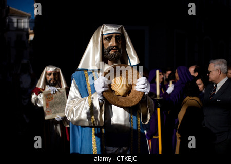 Ein maskierter Mann gekleidet wie eine biblische Figur eine Schale während einer Prozession der Karwoche in Puente Genil, Spanien hält Stockfoto