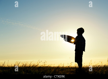 Junge schießen eine Wasserpistole bei Sonnenuntergang. Silhouette. UK Stockfoto