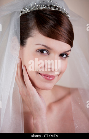 Eine junge Braut trägt ein Diadem und Schleier, hand aufs ruht auf ihrem Gesicht Stockfoto