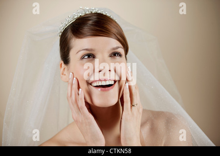 Eine junge Braut, Lächeln, Hände ruhen auf ihrem Gesicht Stockfoto