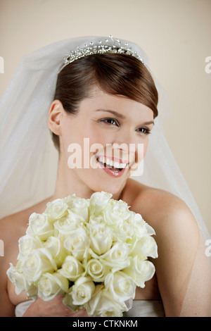 Eine junge Braut hält einen Strauß weiße Rosen, Lächeln Stockfoto