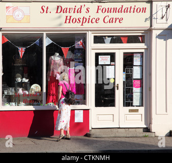 Frau, die in das Fenster von einem Hospiz-Charity-Shop in Monmouth, Wales, UK Stockfoto