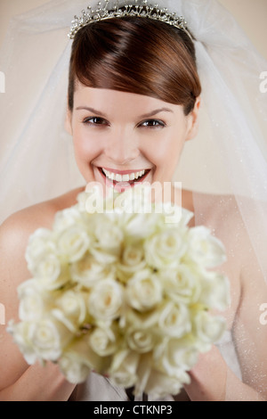 Eine junge Braut hält einen Strauß weiße Rosen, Lächeln und Kamera Stockfoto