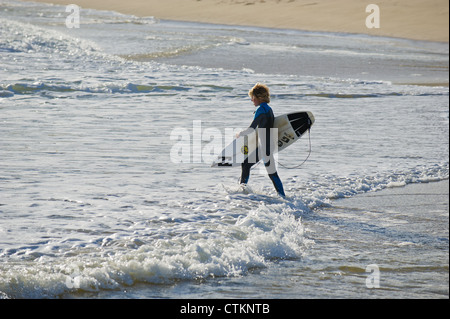 Ein junger Surfer sein Surfbrett mit in das Meer bei Margaret River Stockfoto