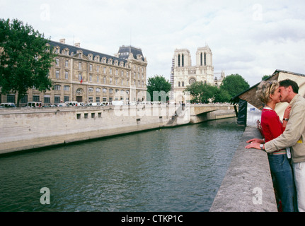 Ein paar küssen entlang der Seine in Paris, Frankreich mit der Notre Dame Kathedrale im Hintergrund. Stockfoto