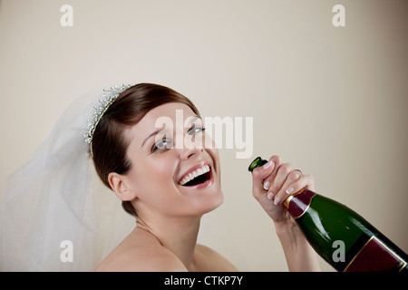 Eine junge Braut hält eine Flasche Champagner Stockfoto