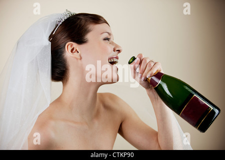 Eine junge Braut hält eine Flasche Champagner Stockfoto