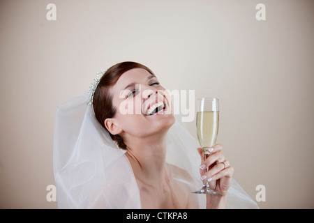 Eine junge Braut hält ein Glas Champagner, lachen