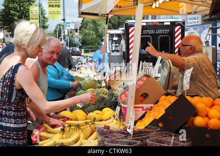 Menschen kaufen Obst und Gemüse aus einem Stall in Portsmouth Straße Markt England UK Stockfoto