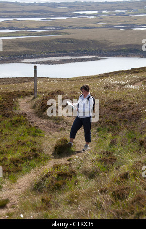 Isle of North Uist, Schottland. Lady Walker überprüfen ihr OS Map auf Beinn Langais mit Loch Langais im Hintergrund. Stockfoto