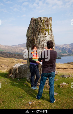 Ein Mann, ein Bild von einer Frau neben einer Felsformation an der Küste in der Nähe von Kenmare; County Kerry, Irland Stockfoto