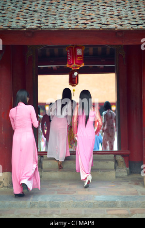Eine Gruppe von jungen Frauen, gekleidet in traditionellen Ao Dai Kleider walking in The Temple of Literature Stockfoto