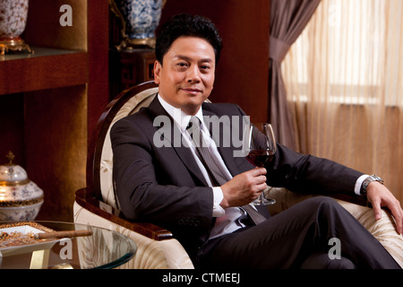 Reife Geschäftsmann Weingenuss in einem luxuriösen Zimmer Stockfoto
