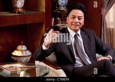 Reife Geschäftsmann Weingenuss in einem luxuriösen Zimmer Stockfoto