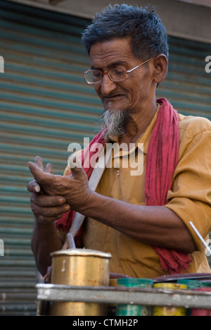 Ältere Mann reiben Pfanne in der Hand - Mumbai, Indien Stockfoto