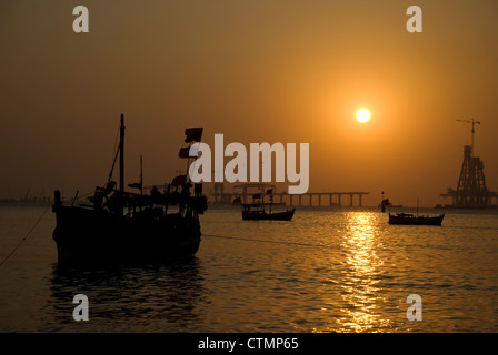 Silhouette von Fähren und Boote während des Sonnenuntergangs - Mumbai, Indien. Bau von Worli Sea Link im Hintergrund Stockfoto