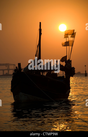 Silhouette einer Fähre während des Sonnenuntergangs - Mumbai, Indien. Bau von Worli Sea Link im Hintergrund Stockfoto