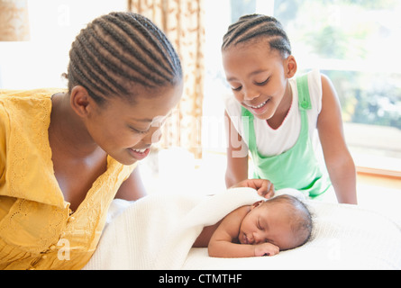 Mutter und junges Mädchen wachen über Neugeborene schlafen auf Bett in Johannesburg, Südafrika Stockfoto