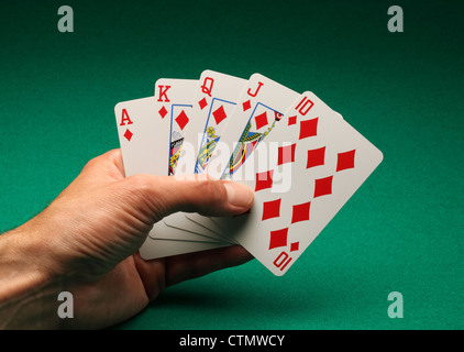 Eines Mannes Hand mit Spielkarten am grünen Tisch. Ein Royal Flush von Diamanten in das Spiel von Poker Stockfoto