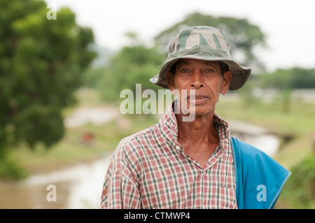 Ein Bild von einen alten thailändischen männlichen Dorfbewohner trägt ein kariertes Hemd und eine Armee Hut. Aufgenommen im Freien durch lokale Kanal Phetburi Thailand Stockfoto