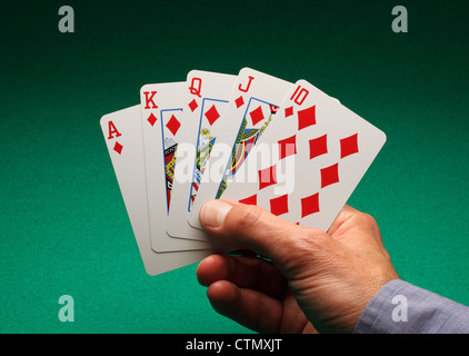 Eines Mannes Hand mit Spielkarten am grünen Tisch. Ein Royal Flush von Diamanten in das Spiel von Poker Stockfoto