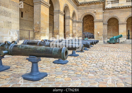 Antike Kanonen stehen in der Reihe am gepflasterten Hof im Museum von Les Invalides in Paris, Frankreich. Stockfoto