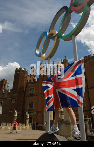 London-Lady steht für ein Erinnerungsfoto auf die Olympischen Ringe, die am Eingang des König Heinrich der achtes Hampton Court Palace am ersten Tag des Wettbewerbs der Straßenrennen der Olympischen Spiele London 2012 250 km Mens stehen. Ausgehend vom Zentrum von London und berühmten Wahrzeichen der Hauptstadt vor der Überschrift heraus in ländlichen England an den zermürbenden Box Hill in der Grafschaft Surrey. Lokalen Südwest Londoner säumten die Strecke, in der Hoffnung auf britische Favorit Mark Cavendish gewinnt Team GB erste Medaille aber schließlich enttäuscht wenn Kasachstans Alexandre Vinokourov schließlich Gold gewann. Stockfoto