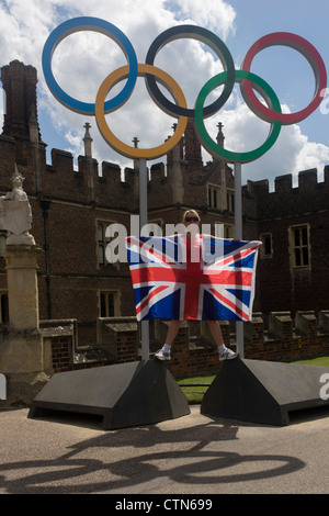 London-Lady steht für ein Erinnerungsfoto auf die Olympischen Ringe, die am Eingang des König Heinrich der achtes Hampton Court Palace am ersten Tag des Wettbewerbs der Straßenrennen der Olympischen Spiele London 2012 250 km Mens stehen. Ausgehend vom Zentrum von London und berühmten Wahrzeichen der Hauptstadt vor der Überschrift heraus in ländlichen England an den zermürbenden Box Hill in der Grafschaft Surrey. Lokalen Südwest Londoner säumten die Strecke, in der Hoffnung auf britische Favorit Mark Cavendish gewinnt Team GB erste Medaille aber schließlich enttäuscht wenn Kasachstans Alexandre Vinokourov schließlich Gold gewann. Stockfoto