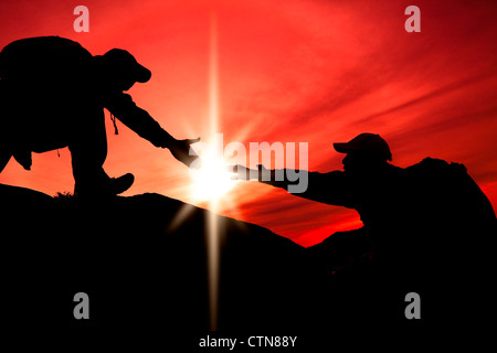 Silhouette der helfende Hand zwischen zwei Kletterer Stockfoto