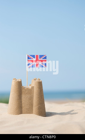 Union Jack-Flagge in eine Sandburg am Strand. Brunnen neben das Meer. Norfolk, England Stockfoto