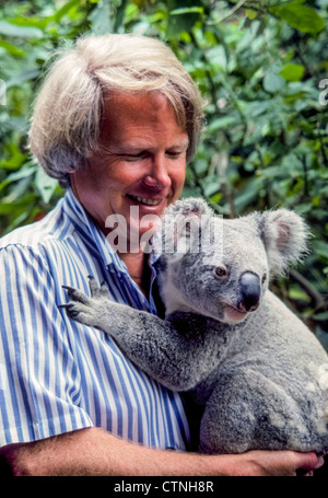 Ein männlicher Besucher kuschelt einen Koala (Phascolarctos Cinereus) an der Lone Pine Koala Sanctuary in Brisbane, Queensland, Australien. Stockfoto