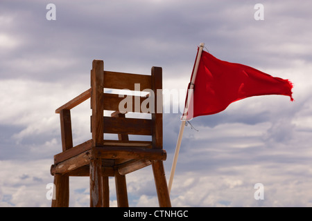 Rettungsschwimmer Stuhl sitzend mit einer roten Fahne im Wind, mit unsicheren Bedingungen zum Schwimmen streaming leer. Stockfoto