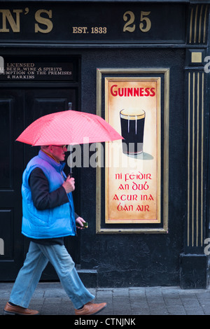 Ein Mann geht vorbei an einem örtlichen Pub im Regen in Kilkenny, Leinster, Irland. Stockfoto