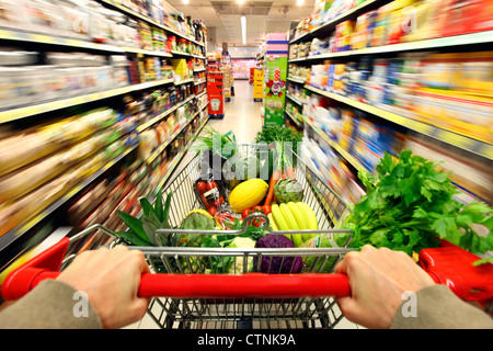 Essen Halle, voller Einkaufswagen wird durch einen Flur mit mehreren Nahrungsmitteln geschoben. Grosser Supermarkt, Self-Service. Stockfoto