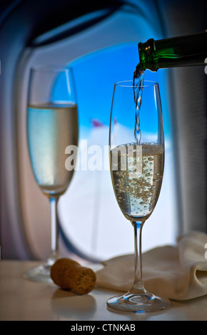 Französischen Champagner während des Fluges in Luxus-Kabine mit Fenster und Flugzeug Flügel hinter gießen Stockfoto