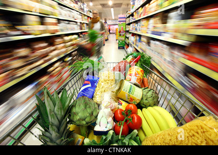 Essen Halle, voller Einkaufswagen wird durch einen Flur mit mehreren Nahrungsmitteln geschoben. Grosser Supermarkt, Self-Service. Stockfoto