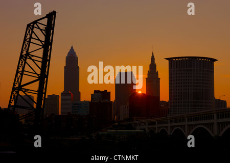 Die Sonne geht über eines der Innenstadt Gebäude und wirft ein orange Leuchten am Himmel hinter der Skyline von Cleveland, Ohio. Stockfoto