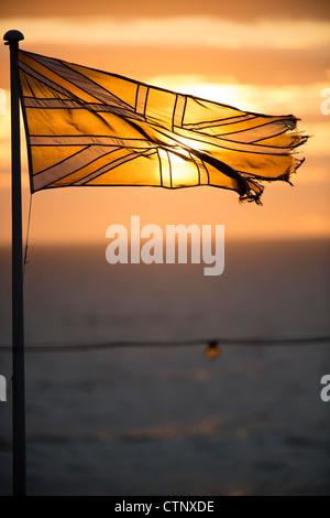 Ein Sonnenuntergang über ein Ol zerfetzten Semi transparent britischen Union Jack Fahnenbanner Stockfoto