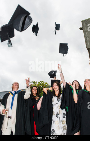 Studenten werfen, werfen ihre Mörtel-Boards in der Luft am Abschlusstag der Aberystwyth University Student, Juli 2012 Stockfoto