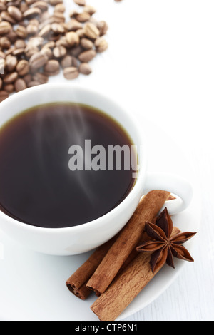 Tasse heißen Kaffee mit Zimt-Sticks, Sternanis und Kaffeebohnen auf einem weißen Tisch Stockfoto