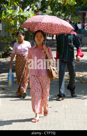 Burmesische Frau zu Fuß im Schatten eines Sonnenschirms in Yangon (Rangoon), Myanmar (Burma). Stockfoto