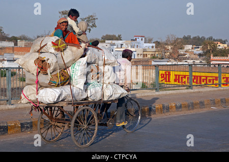 Dreirad-Rikscha, die Beförderung von Kindern sitzen auf schwere Last in Agra, Uttar Pradesh, Indien Stockfoto